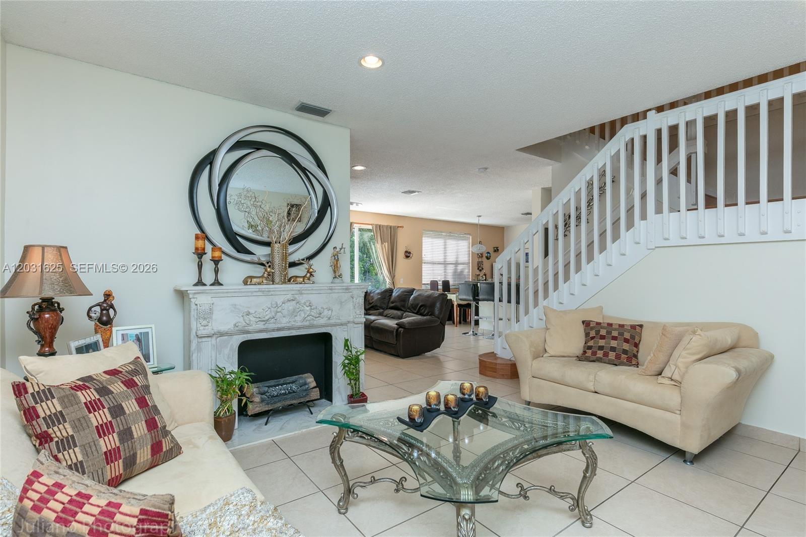 A living room features a marble fireplace, a glass coffee table, and a white staircase — 1032 Silktree Ln, Weston FL 33327, WESTON, FL