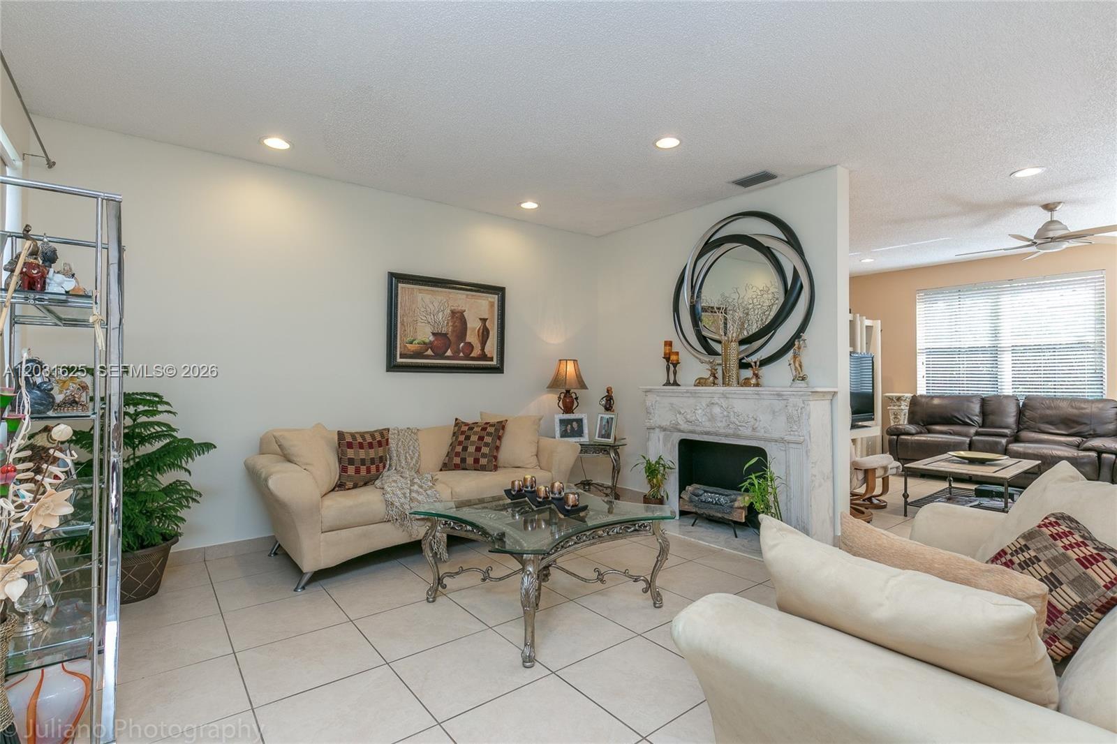 A living room features a fireplace, tile flooring, and two beige sofas — 1032 Silktree Ln, Weston FL 33327, WESTON, FL
