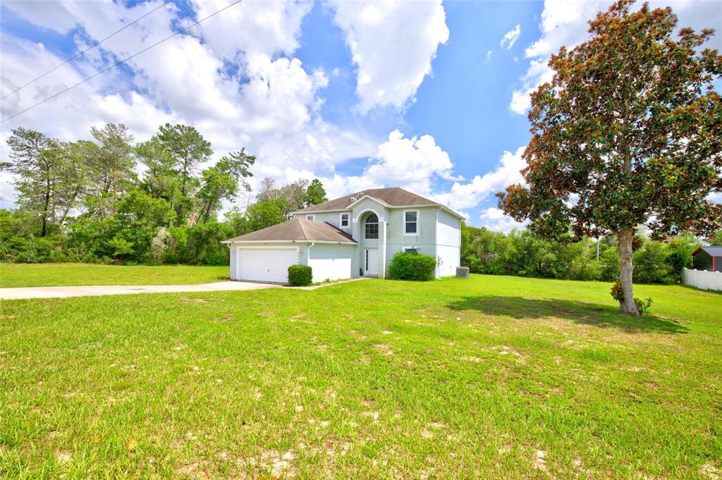 A two-story house with a white garage and a large front yard under a blue sky — 3960 SW 110TH LANE, OCALA, FL