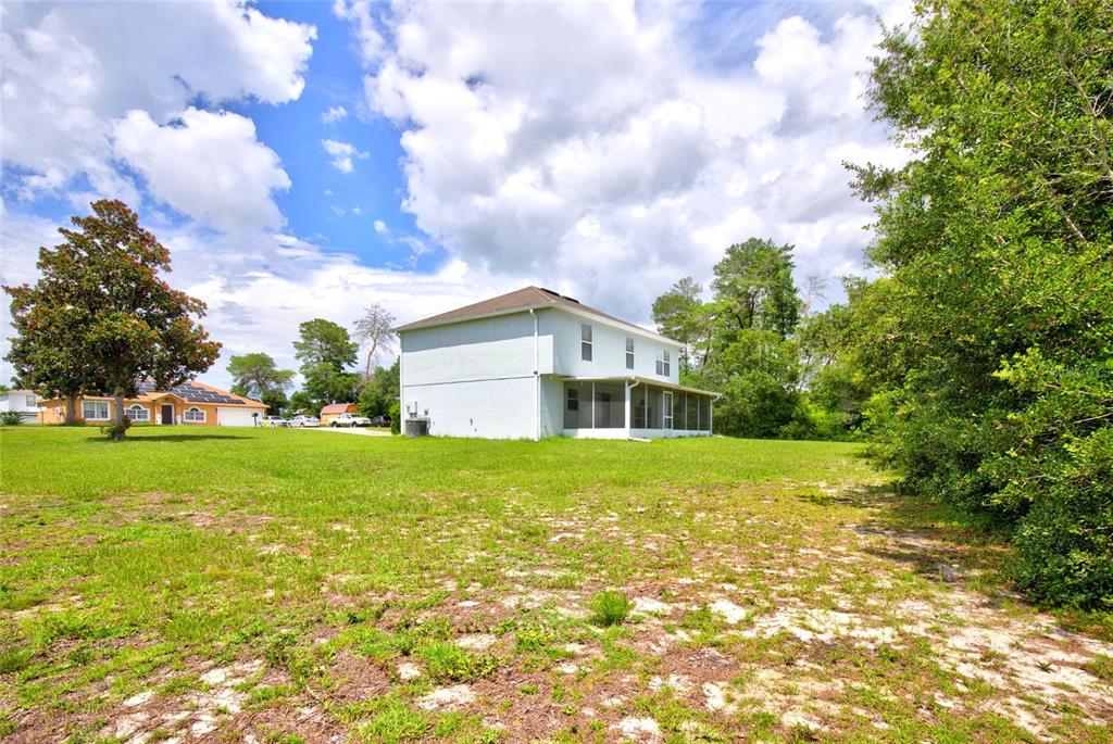 A two-story light-colored house with a screened porch sits on a large, grassy lot — 3960 SW 110TH LANE, OCALA, FL