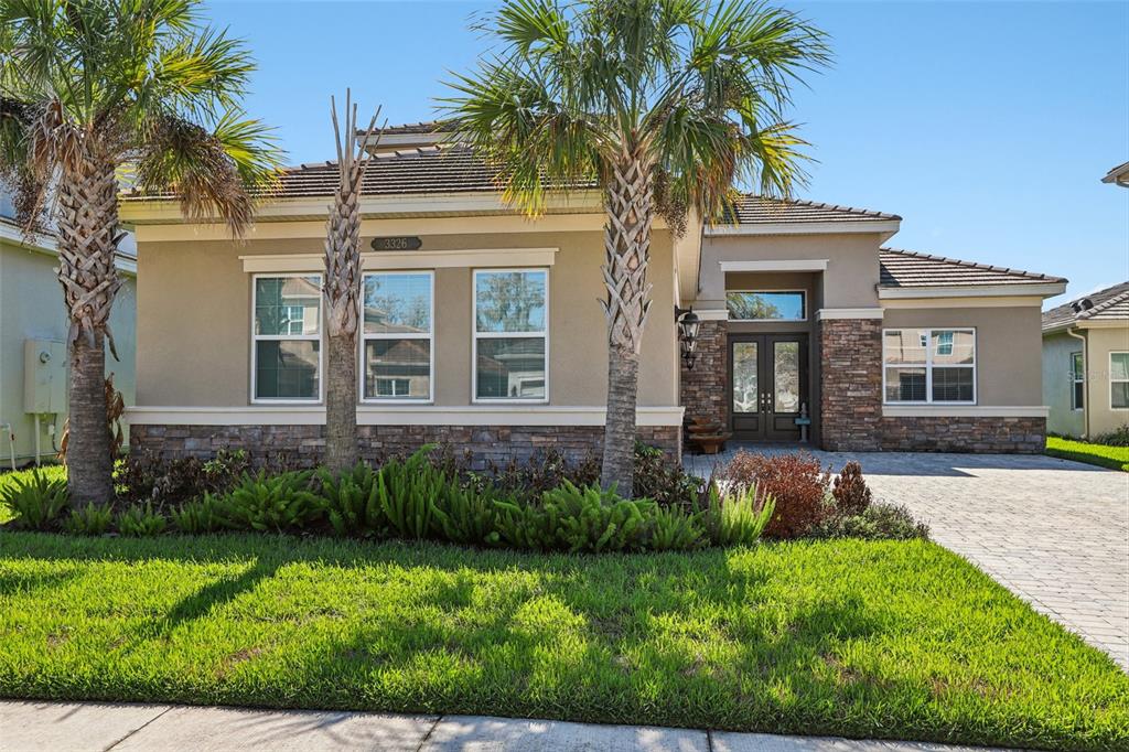 A single-story house with a stone facade, palm trees, and a paved driveway — 3326 ACACIA BAY AVENUE, WESLEY CHAPEL, FL