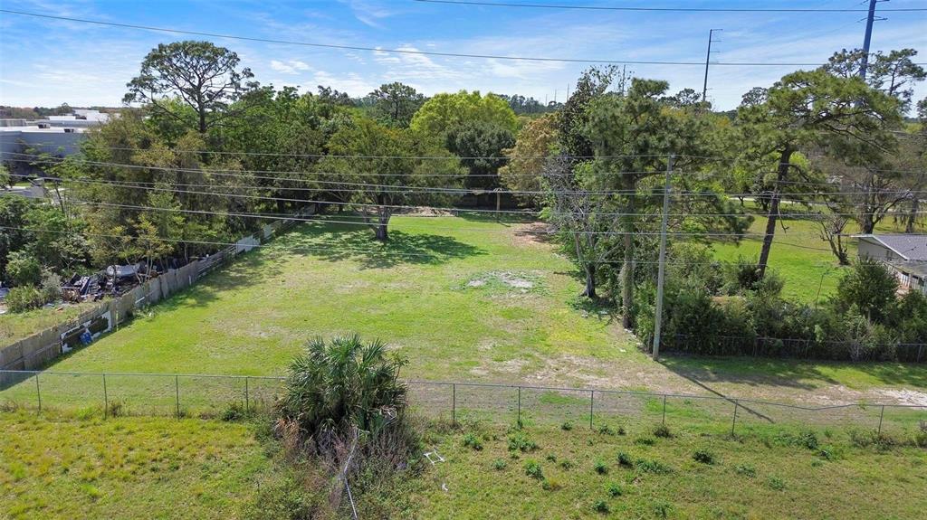 An aerial view shows a flat, grassy vacant lot enclosed by a chain-link fence — 11602 IROQUOIS TRAIL, ORLANDO, FL