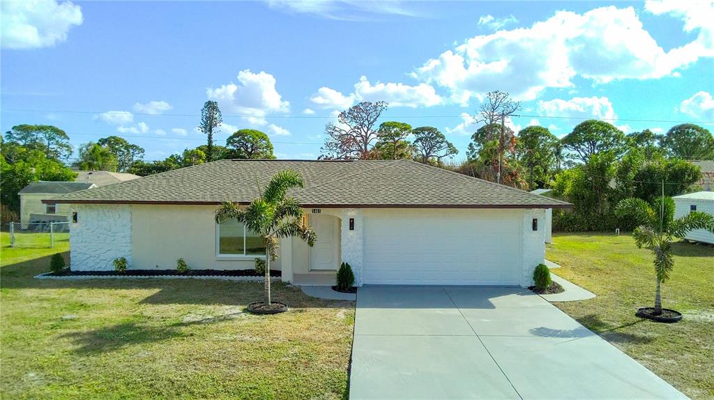 A single-story house with a white garage, light-colored walls, and two small palm trees — 1461 ROYAL ROAD, VENICE, FL