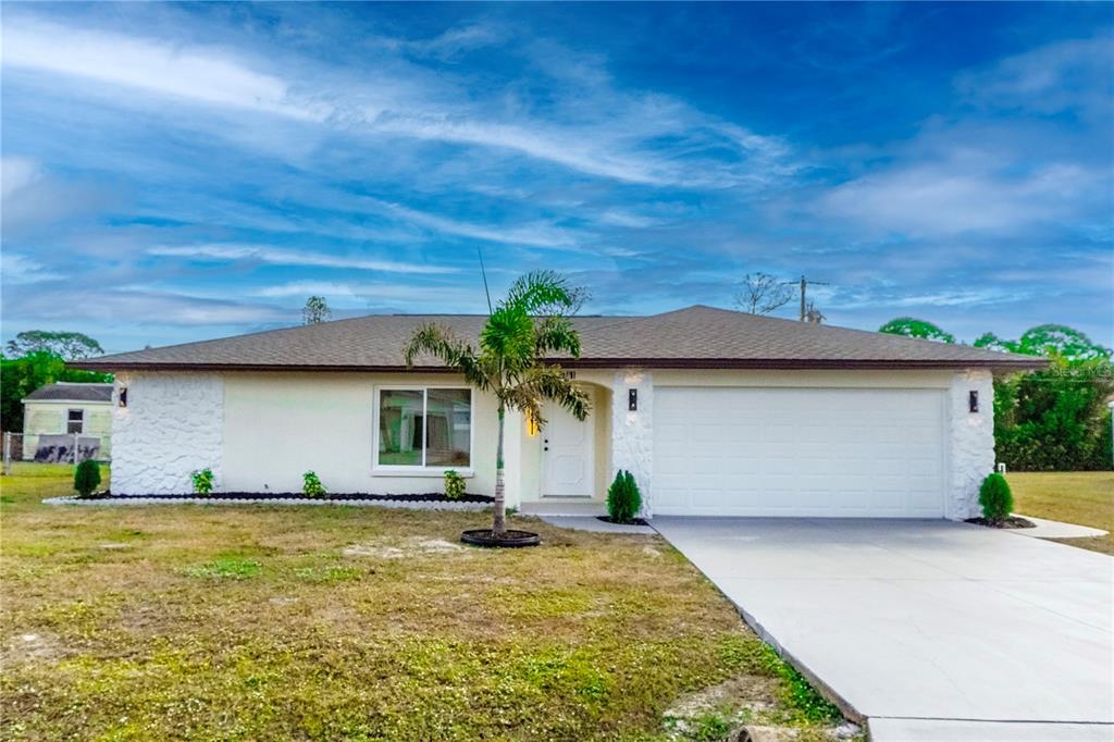 A single-story house with a white stucco facade, stone accents, and a two-car garage — 1461 ROYAL ROAD, VENICE, FL
