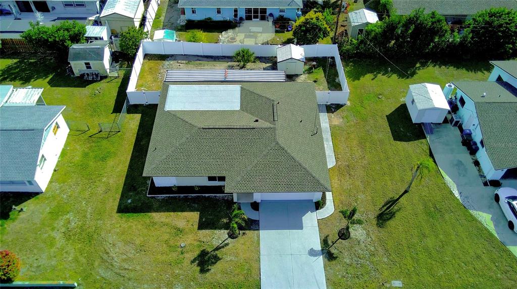 An aerial view shows a single-story house with a green roof and a fenced backyard — 1461 ROYAL ROAD, VENICE, FL