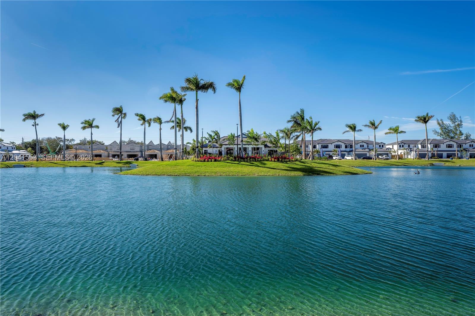 A lake sits in the foreground before a landscaped island with palm trees and houses — 5001 Peacock Way # 5838, Dania Beach FL 33312, DANIA BEACH, FL
