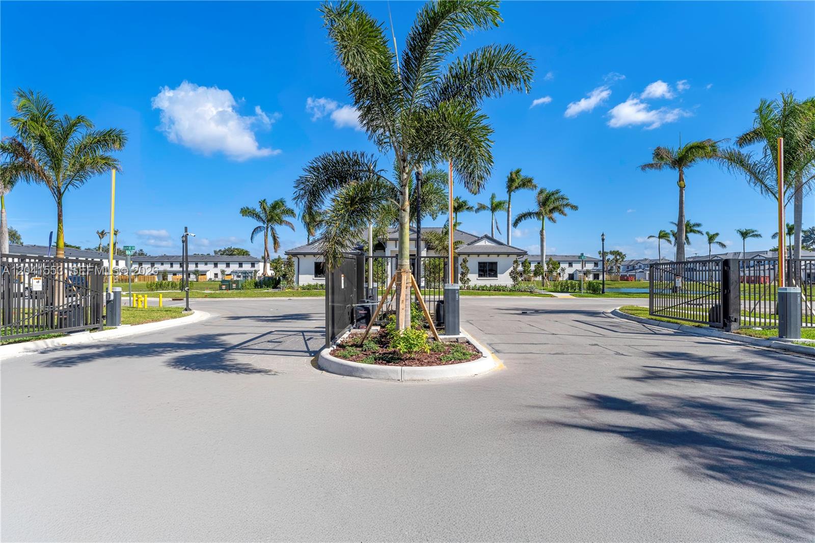 A gated entrance with palm trees and a clubhouse in the background under a blue sky — 5001 Peacock Way # 5838, Dania Beach FL 33312, DANIA BEACH, FL