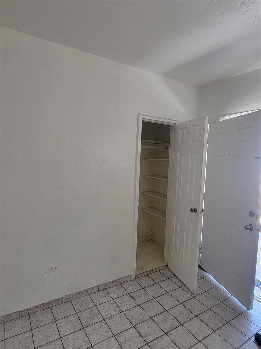 A room with white walls, tiled flooring, an open closet, and an open exterior door — 1822 Johnson Street, Hollywood FL 33020, HOLLYWOOD, FL