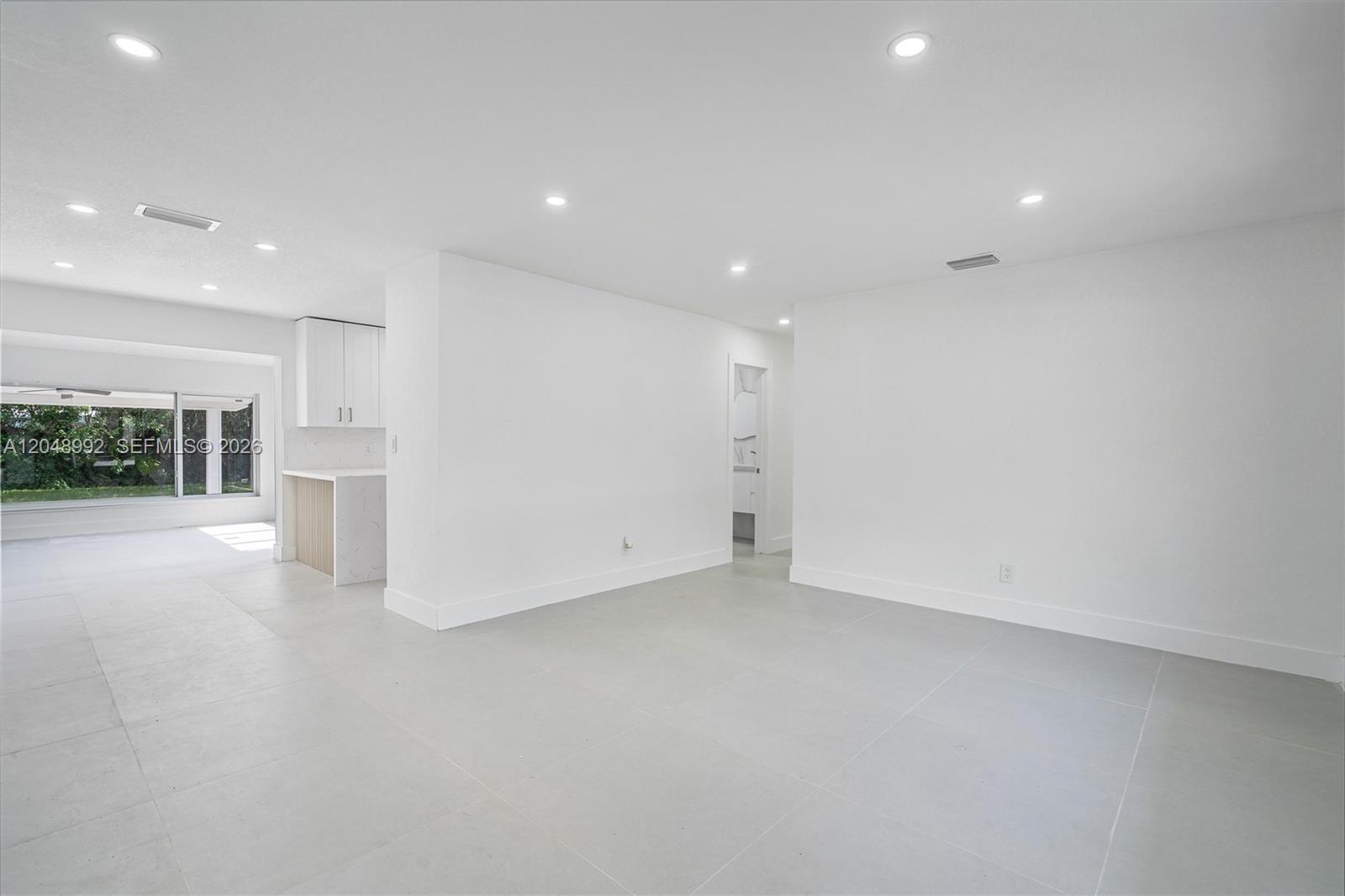 A bright, minimalist living area features white walls, recessed lighting, and large light-gray floor tiles — 321 NW 36th St, Oakland Park FL 33309, OAKLAND PARK, FL