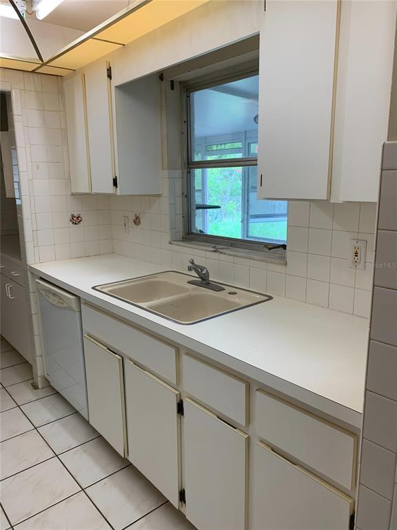 A kitchen features white cabinets, a double sink, white tile countertops, and a window — 9598 RIVER ROAD, SPRING HILL, FL