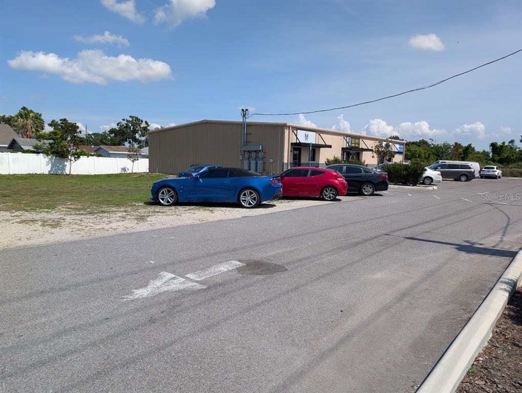 A commercial building exterior with a parking lot containing several cars — 7019 N MANHATTAN AVENUE, TAMPA, FL