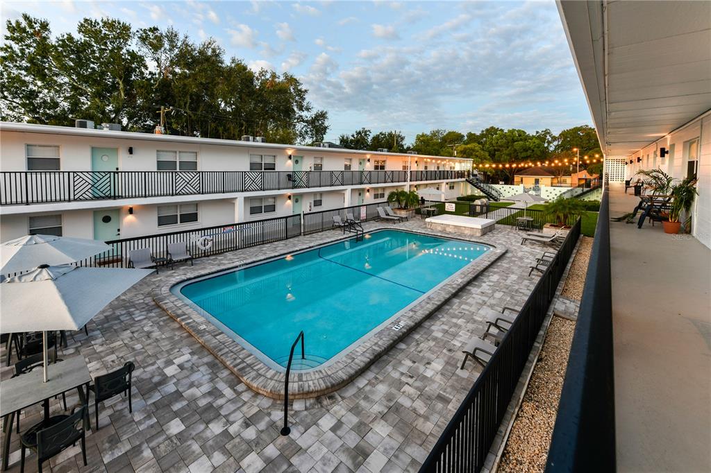 An elevated view of a rectangular swimming pool surrounded by a paved patio and apartment building — 807 S HOWARD AVENUE UNIT 209, TAMPA, FL