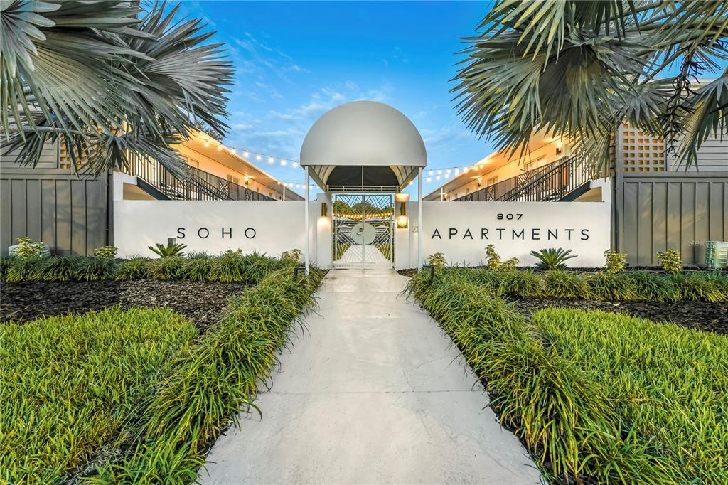 A walkway leads to the entrance of an apartment complex with a white arched canopy — 807 S HOWARD AVENUE UNIT 209, TAMPA, FL