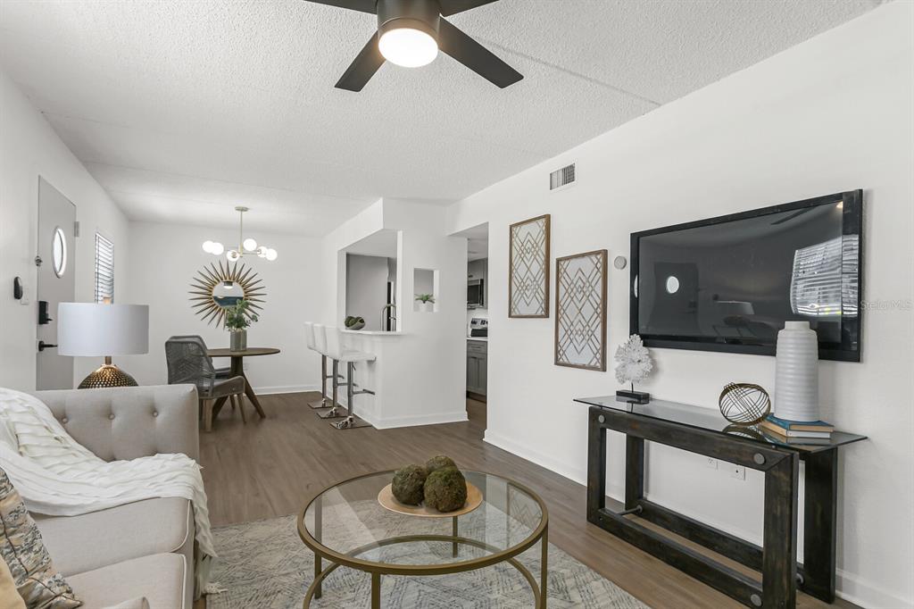 A living room with wood-look flooring, a ceiling fan, and an adjacent dining area — 807 S HOWARD AVENUE UNIT 209, TAMPA, FL