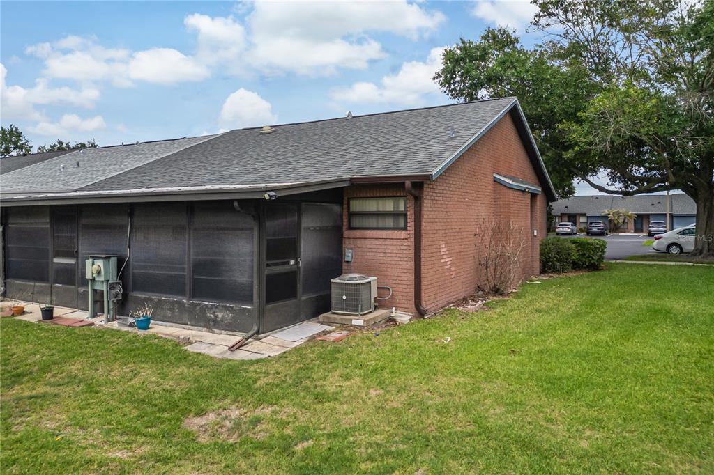 The exterior of a brick townhouse features a screened-in patio and an outdoor AC unit — 2818 SHANNON OAK COURT, ST CLOUD, FL