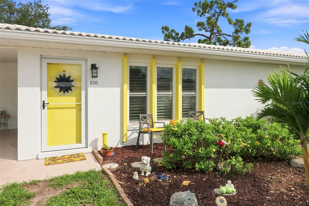 The exterior of a white house features a yellow front door and window trim — 510 CIRCLEWOOD DRIVE UNIT P1-2, VENICE, FL