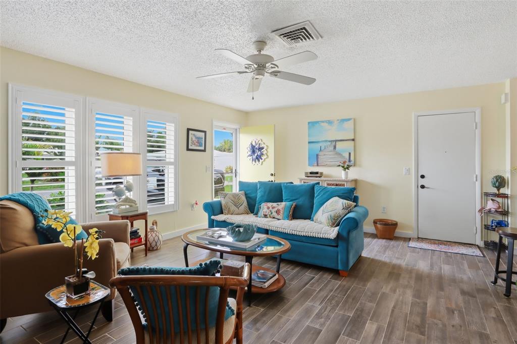 A living room features a blue sofa, a ceiling fan, and tile flooring — 510 CIRCLEWOOD DRIVE UNIT P1-2, VENICE, FL