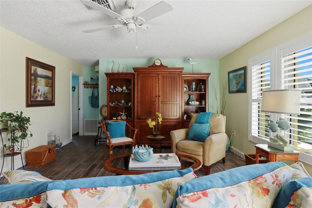 A living room features a large wooden entertainment center, a beige armchair, and tile flooring — 510 CIRCLEWOOD DRIVE UNIT P1-2, VENICE, FL