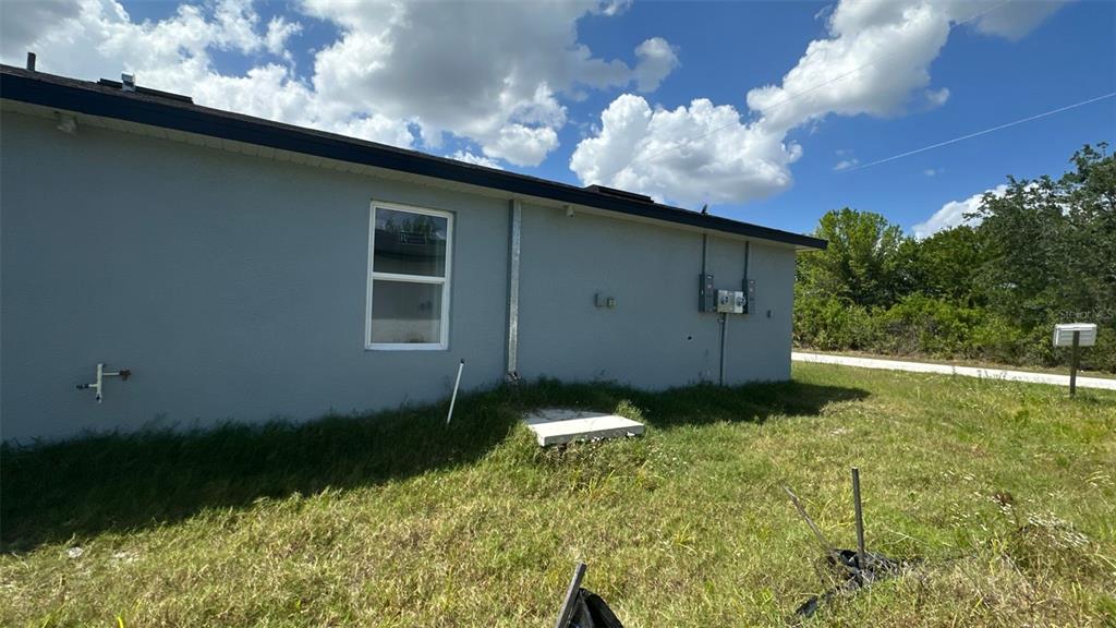 The exterior side of a gray house features a single window and electrical utility boxes — 12223 KIRK AVENUE, PORT CHARLOTTE, FL