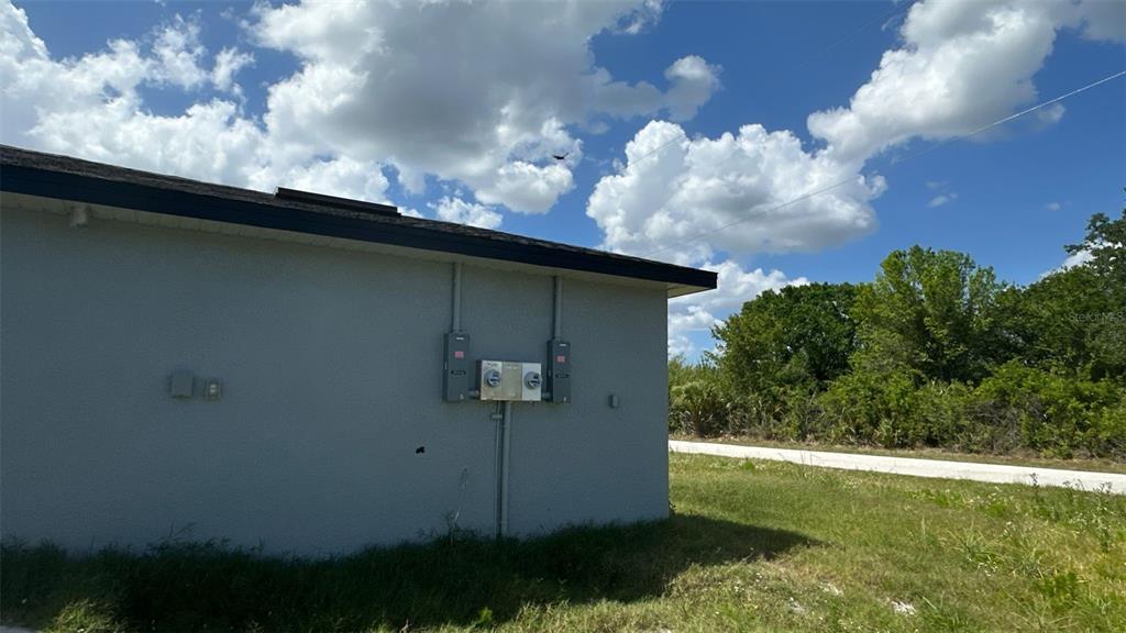 The exterior side wall of a building features two electrical meter boxes and conduit pipes — 12223 KIRK AVENUE, PORT CHARLOTTE, FL