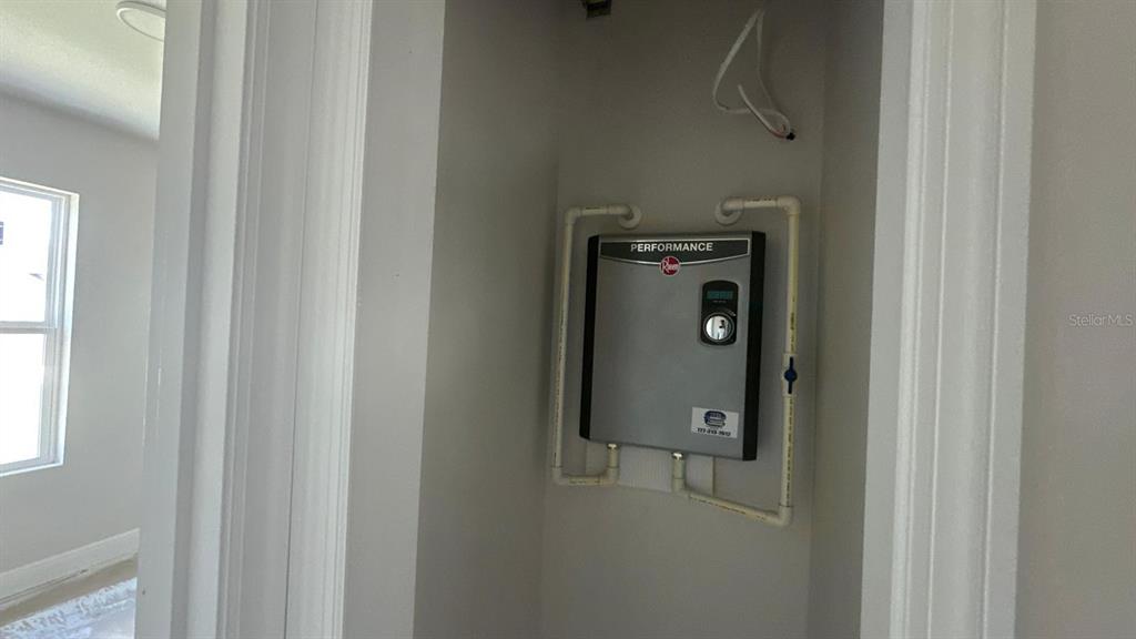 A wall-mounted Rheem electric tankless water heater is installed inside a small utility closet — 12223 KIRK AVENUE, PORT CHARLOTTE, FL