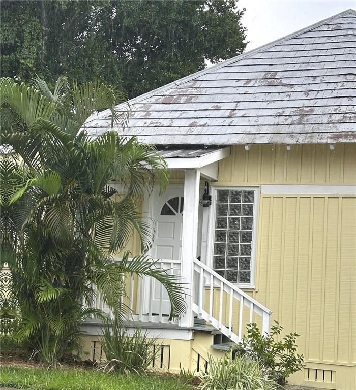 A yellow house exterior features a small porch, a white door, and a glass block window — 109 HIBISCUS STREET UNIT 1, TARPON SPRINGS, FL