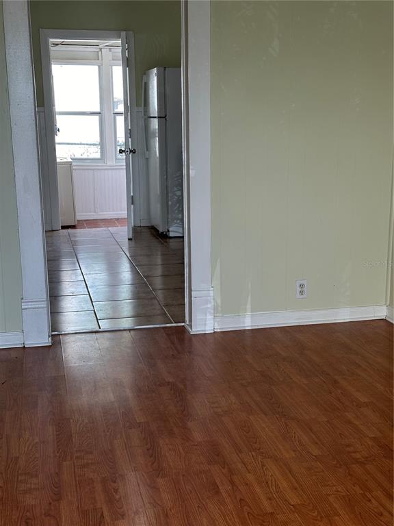A room with wood-look flooring leads through a doorway into a tiled kitchen area — 109 HIBISCUS STREET UNIT 1, TARPON SPRINGS, FL