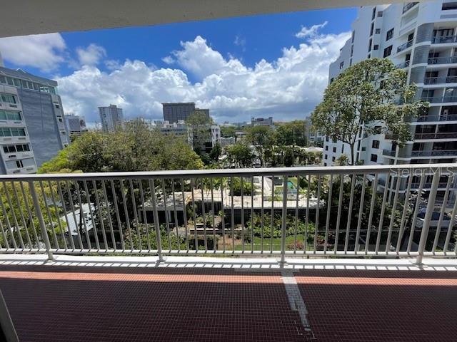 A balcony with a metal railing overlooks a city street, trees, and nearby high-rise buildings — 1367 COND. PIAZZA LUCHETTI UNIT 7-B, SAN JUAN, PR