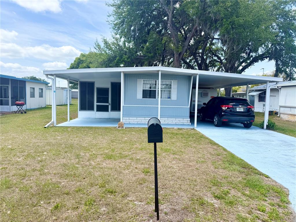 A light blue mobile home features a covered carport, a screened porch, and a mailbox — 4513 AUTUMN PALM DRIVE, ZEPHYRHILLS, FL