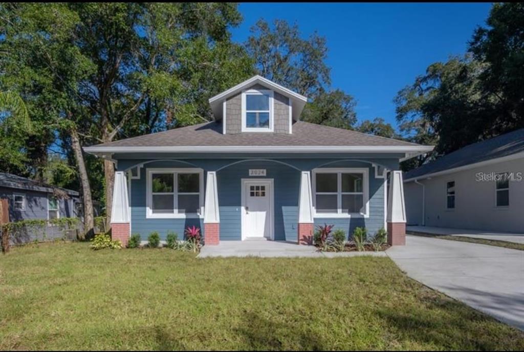 A blue single-story house with a front porch, white columns, and a central dormer window — 7717 AMHERST STREET, TAMPA, FL