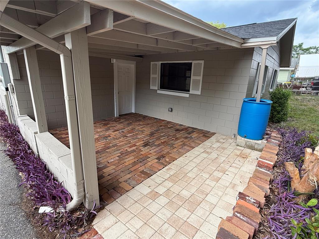 A front porch with a white door, rocking chair, turquoise chair, and potted plants — 1015 W MONTROSE STREET, CLERMONT, FL