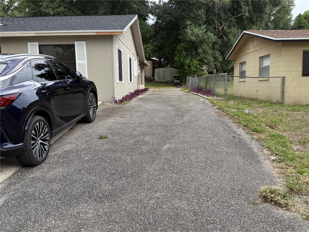 A tan single-story house with a concrete driveway and a brick walkway leading to the entrance — 1015 W MONTROSE STREET, CLERMONT, FL