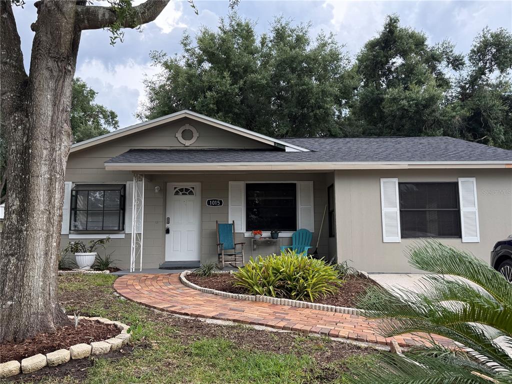 A single-story house with a gray exterior, a concrete driveway, and a large front tree — 1015 W MONTROSE STREET, CLERMONT, FL