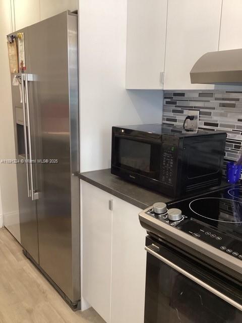 A stainless steel refrigerator stands next to a black microwave on a white kitchen counter — 3133 S Ocean Dr # 118, Hallandale Beach FL 33009, HALLANDALE BEACH, FL