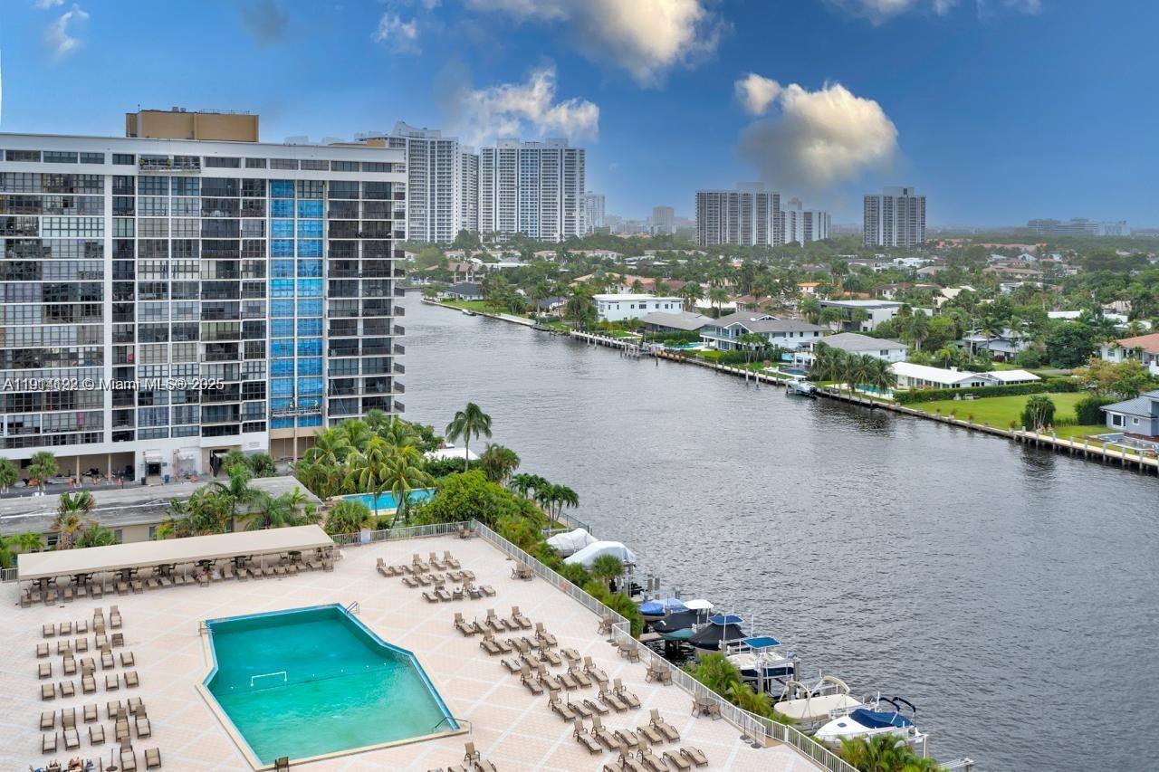 An elevated view shows a swimming pool deck, a canal, and surrounding residential high-rise buildings — 1965 S Ocean Dr # M, Hallandale Beach FL 33009, HALLANDALE BEACH, FL