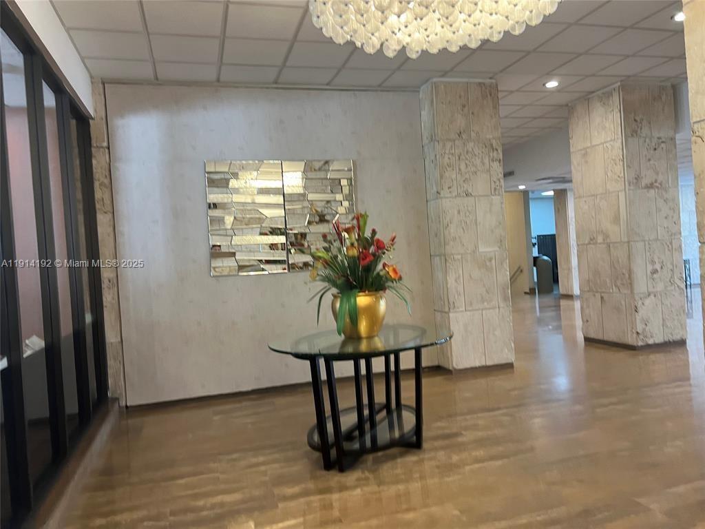 A lobby features a glass-topped table with a floral arrangement against a mirrored wall — 1965 S Ocean Dr # M, Hallandale Beach FL 33009, HALLANDALE BEACH, FL