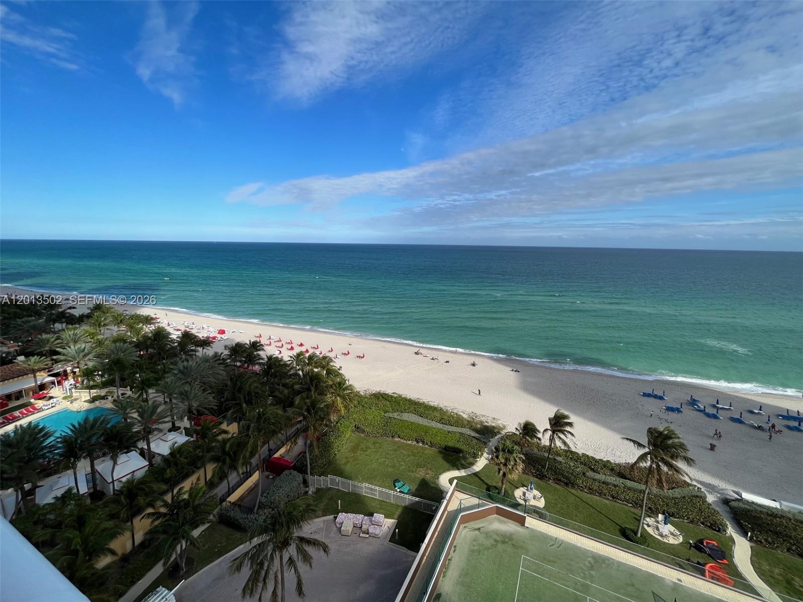 An elevated view of a beach, ocean, palm trees, and a tennis court — SUNNY ISLES BEACH, FL