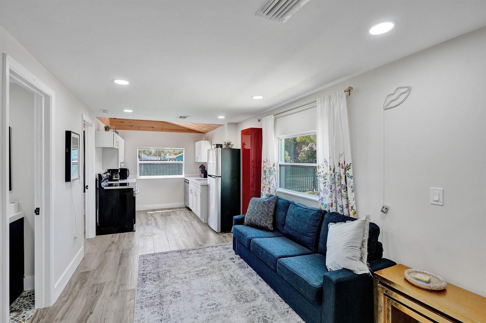 A living room with a blue sofa and rug opens into a kitchen with white cabinets — 8021 NW 1st Place # 1, Miami FL 33150, MIAMI, FL