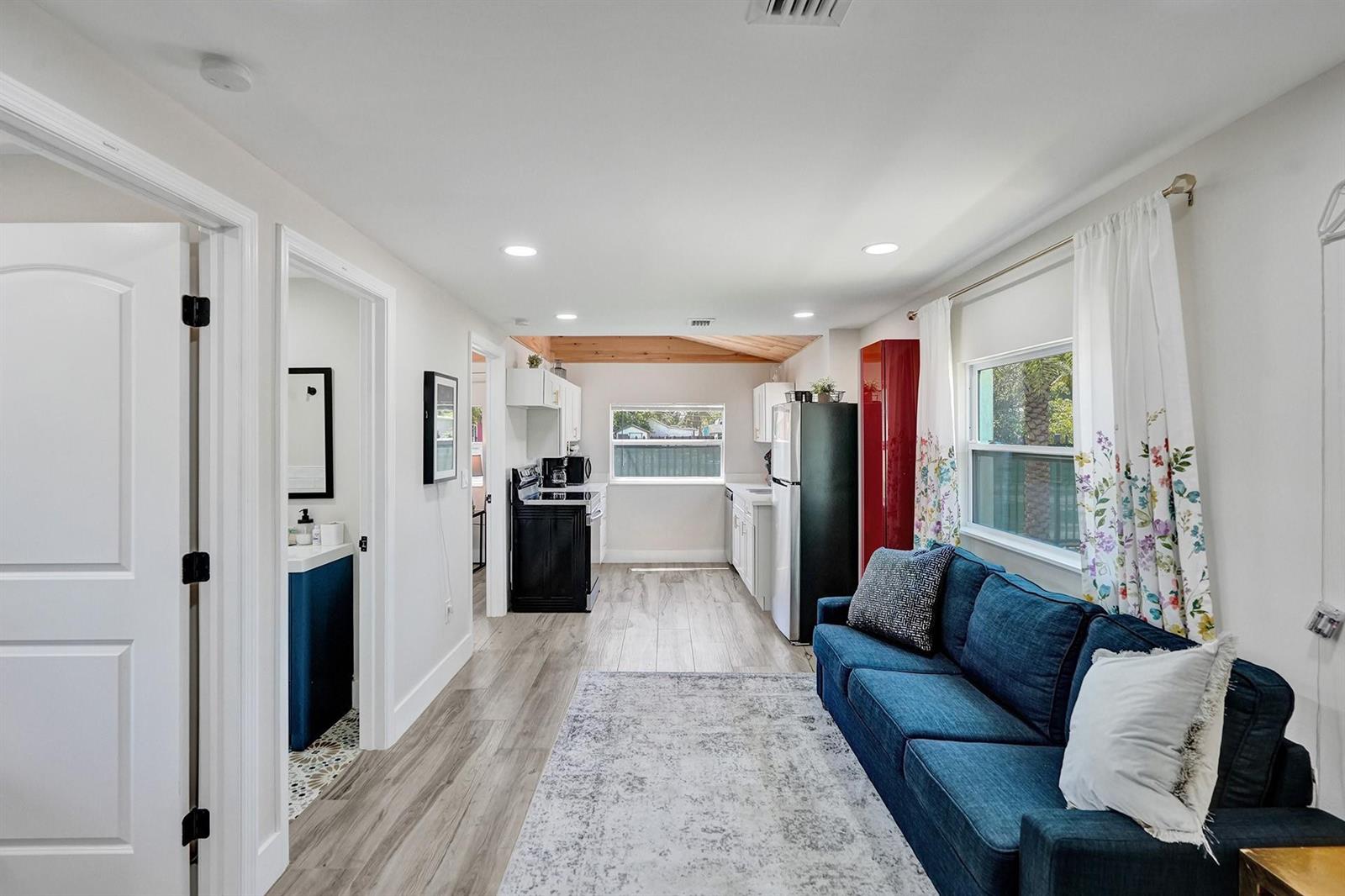 A small living area with a blue sofa opens into a kitchen with white cabinets — 8021 NW 1st Place # 1, Miami FL 33150, MIAMI, FL