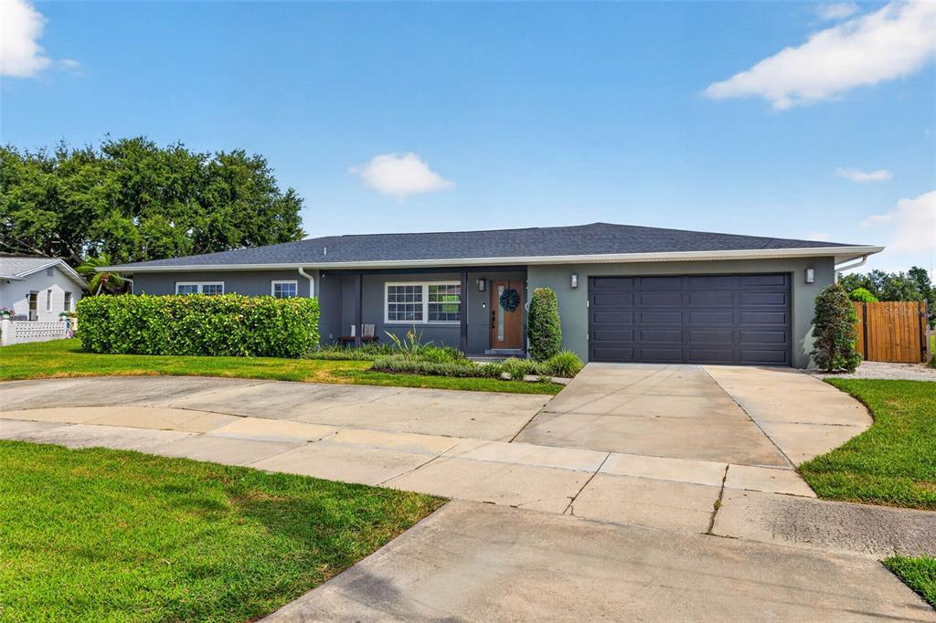 A single-story house with a gray exterior, a two-car garage, and a landscaped front yard — 2101 37TH STREET N, ST PETERSBURG, FL