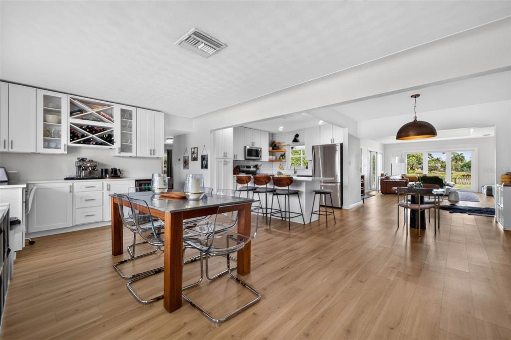 An open-concept kitchen and dining area features light wood flooring, white cabinetry, and a central island — 2101 37TH STREET N, ST PETERSBURG, FL