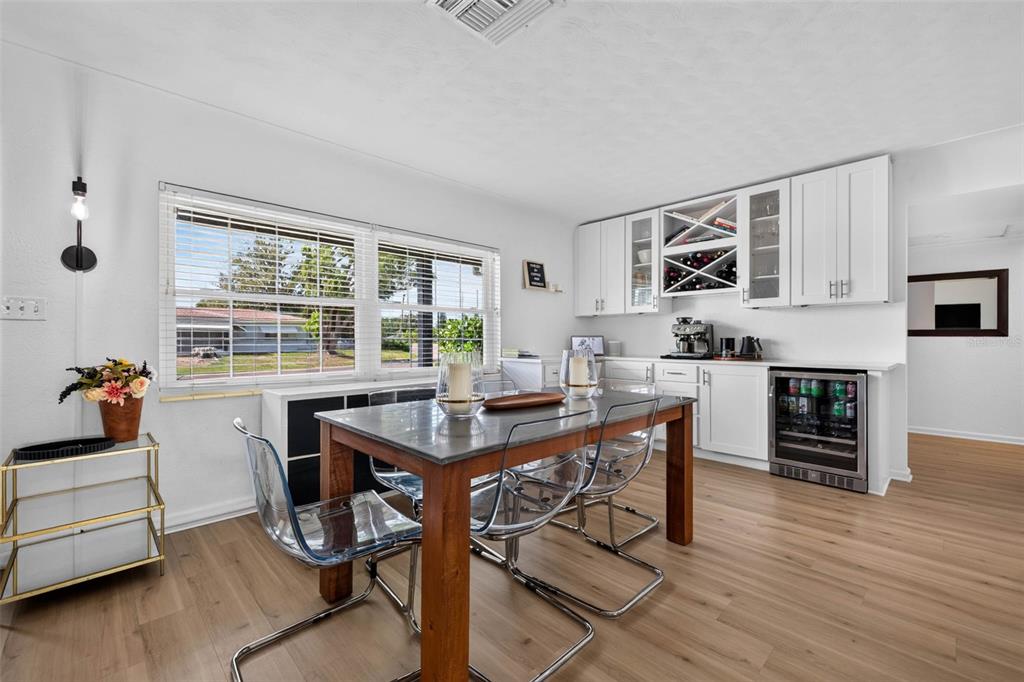 A dining room features a wooden table, clear chairs, white cabinetry, and a wine refrigerator — 2101 37TH STREET N, ST PETERSBURG, FL