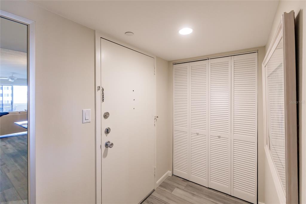 An entryway features a white front door, a louvered closet, and light wood-look flooring — 1055 W PEPPERTREE DRIVE UNIT 506AA, SARASOTA, FL