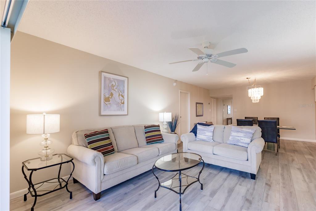 A living room features two beige sofas, a glass coffee table, and light wood flooring — 1055 W PEPPERTREE DRIVE UNIT 506AA, SARASOTA, FL