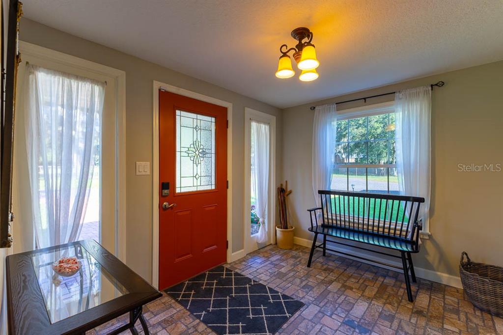 An entryway features a red front door, tiled flooring, a black bench, and a window — 210 WESTLAKE DRIVE, LAKE HELEN, FL
