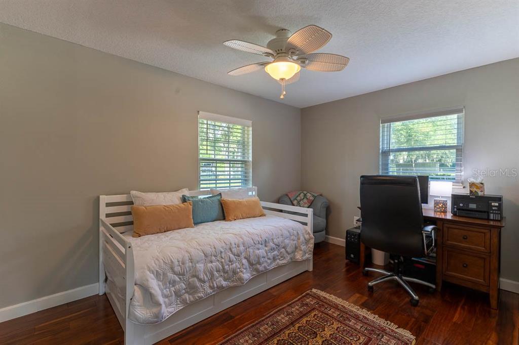 A bedroom features a white daybed, a wooden desk with a chair, and a ceiling fan — 210 WESTLAKE DRIVE, LAKE HELEN, FL