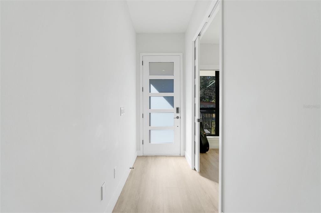 A white hallway leads to a modern front door with horizontal glass panels — 1751 GOODRICH AVENUE, WINTER PARK, FL