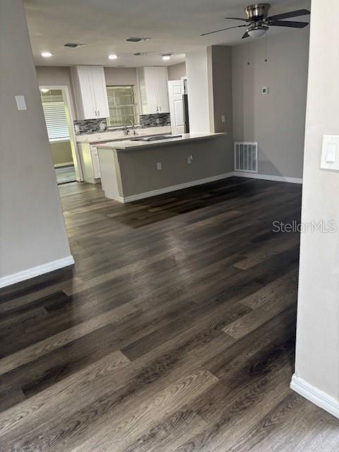 An open-concept kitchen features white cabinets, a breakfast bar, and dark wood-look flooring — 17 S JEFFERSON STREET, BEVERLY HILLS, FL