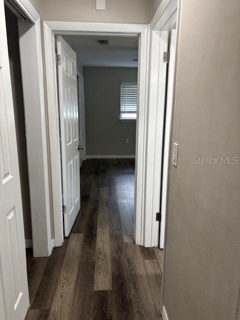 A hallway with wood-look flooring leads to an open doorway showing a room with blinds — 17 S JEFFERSON STREET, BEVERLY HILLS, FL
