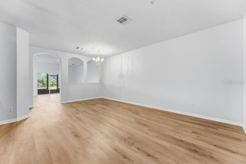 An empty room with light wood-look flooring, white walls, and arched wall niches — 2795 OAKWATER DR, KISSIMMEE, FL